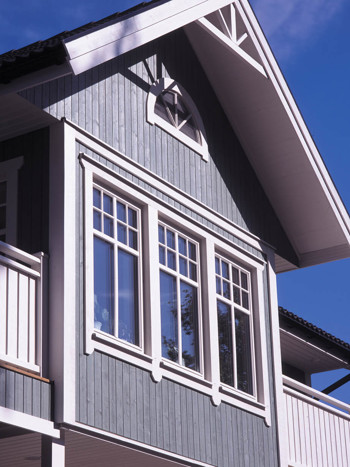 Vita fönster med spröjs på grå träfasad